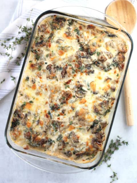 Chicken and mushroom potato bake in a glass baking dish next to a wooden spoon.
