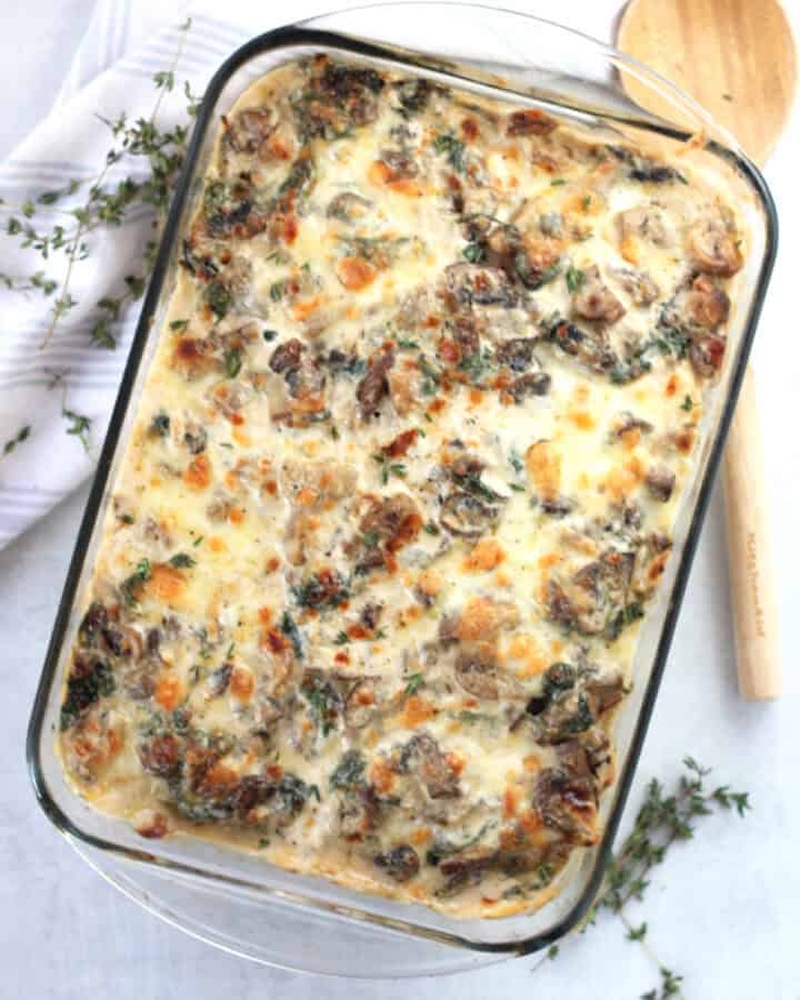 Chicken and mushroom potato bake in a glass baking dish next to a wooden spoon.