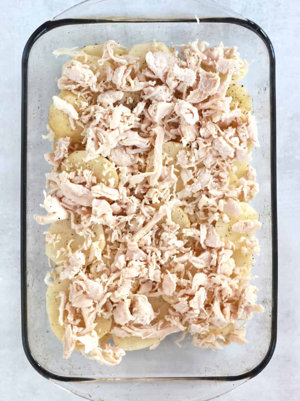 Shredded chicken on top of sliced potatoes.