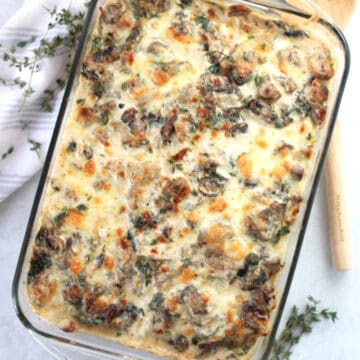 Chicken, mushroom and spinach potato bake in a glass dish garnished with fresh thyme.