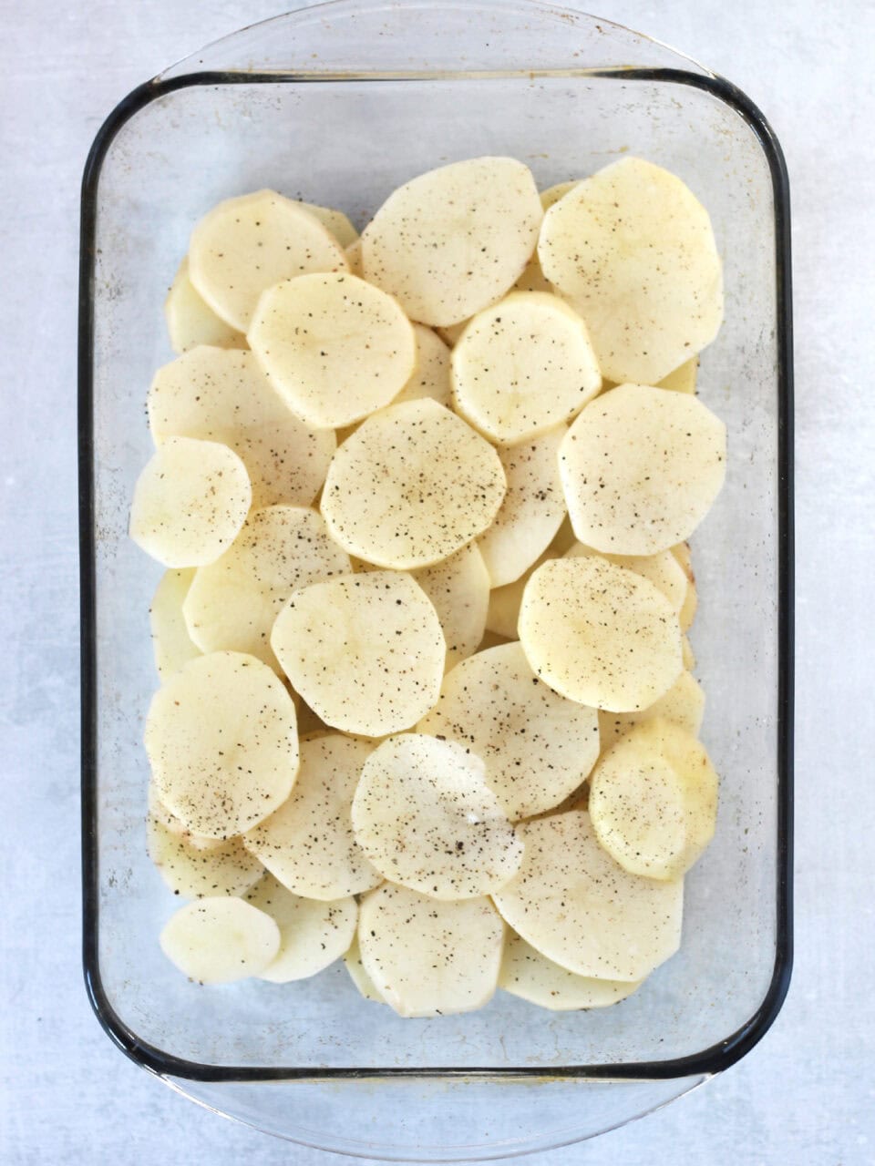Sliced potatoes in a glass baking dish.