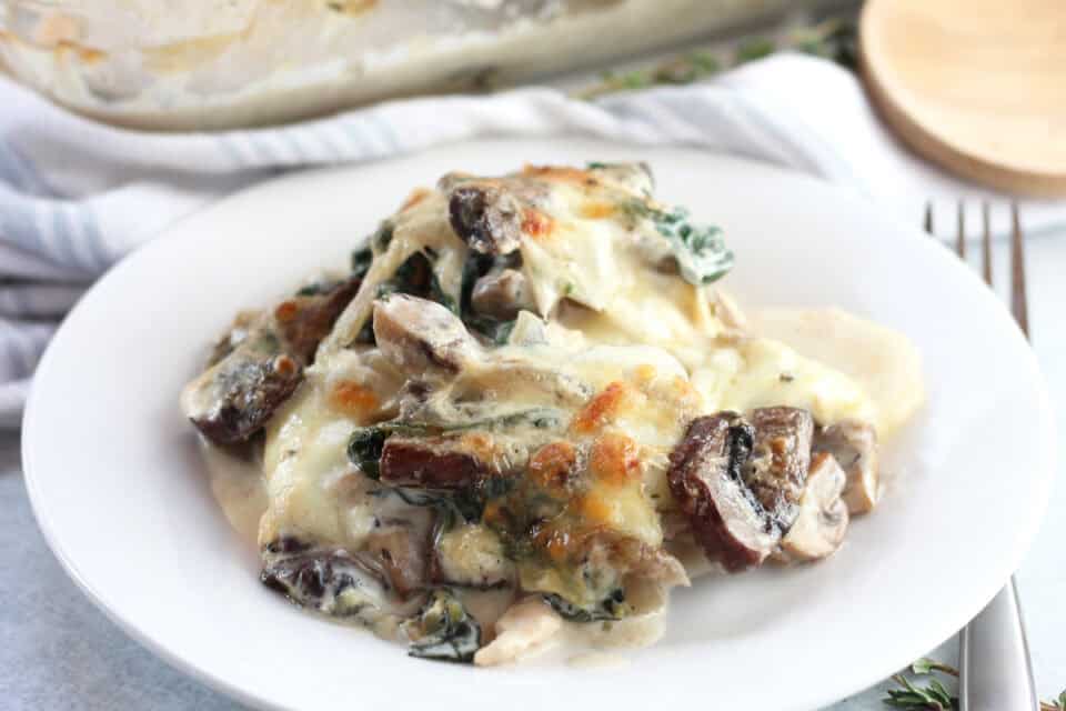 Chicken potato bake with melted cheese served on a white plate.