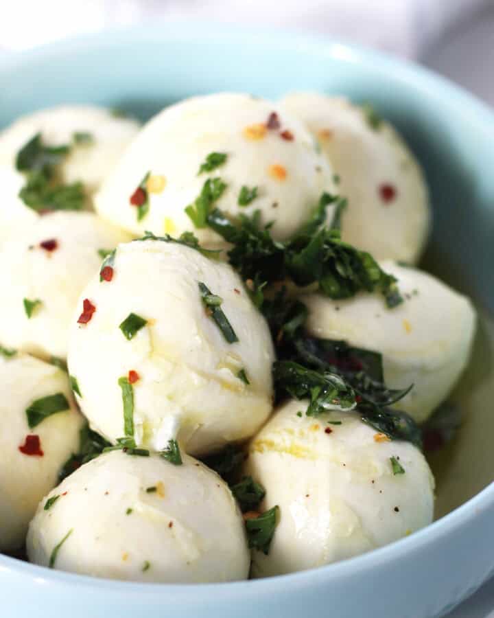 Marinated Bocconcini balls in a blue bowl.