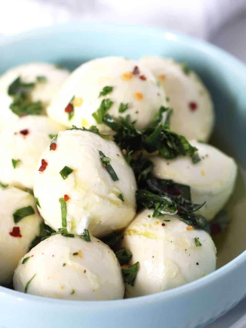 Marinated Bocconcini balls in a blue bowl.