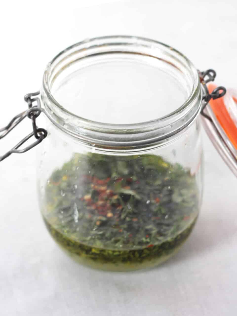 Oil, lemon juice and herbs in a jar.