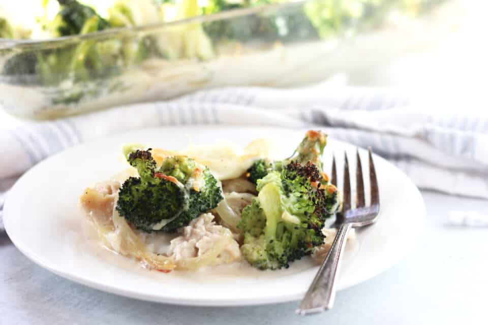 Broccoli, chicken and potato casserole served on a white plate with a fork.
