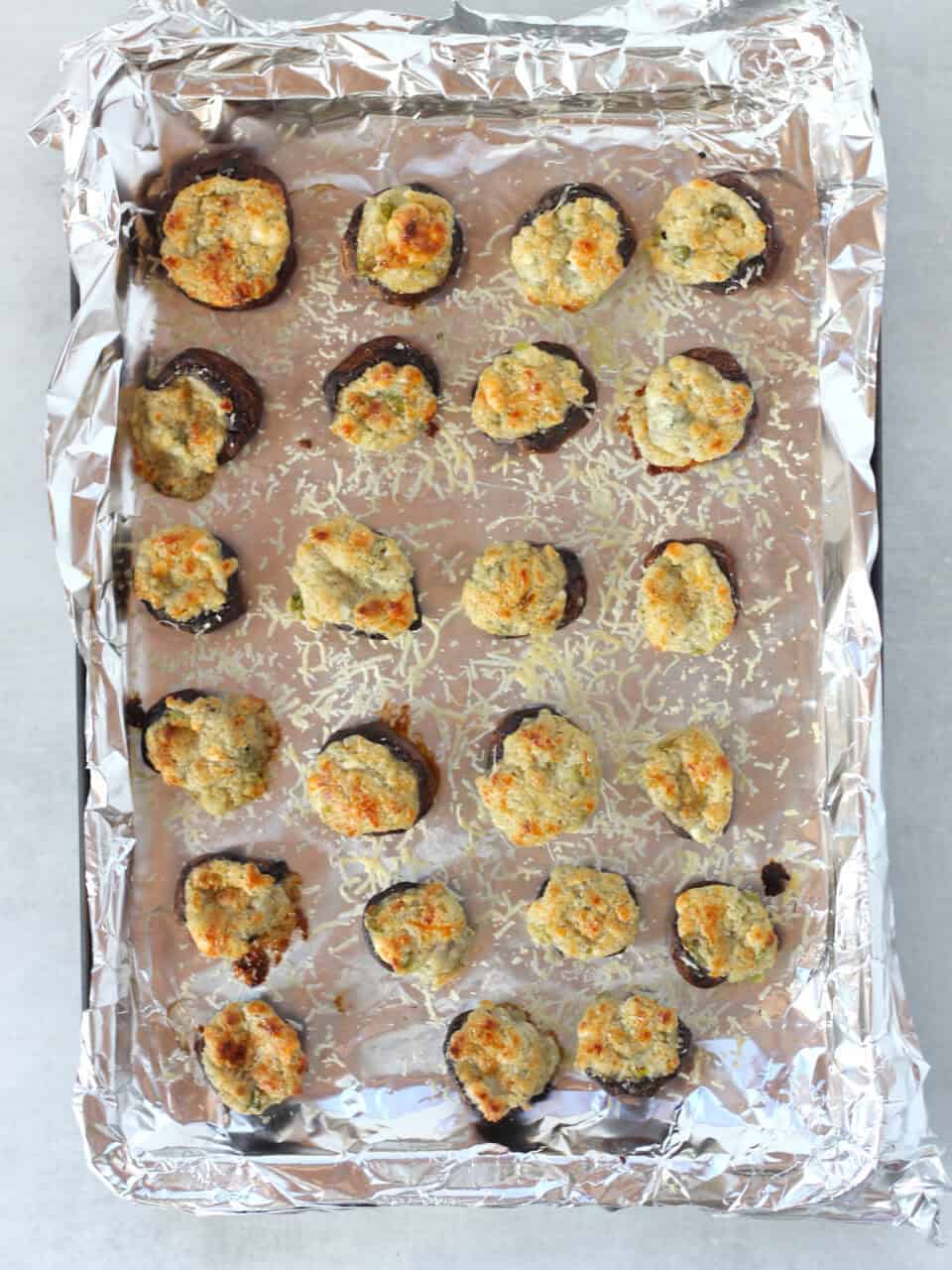 Baked stuffed mushrooms on a foil lined tray.