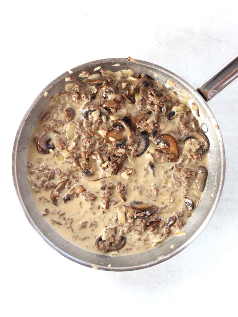 Mushrooms and onions in cream in a skillet.