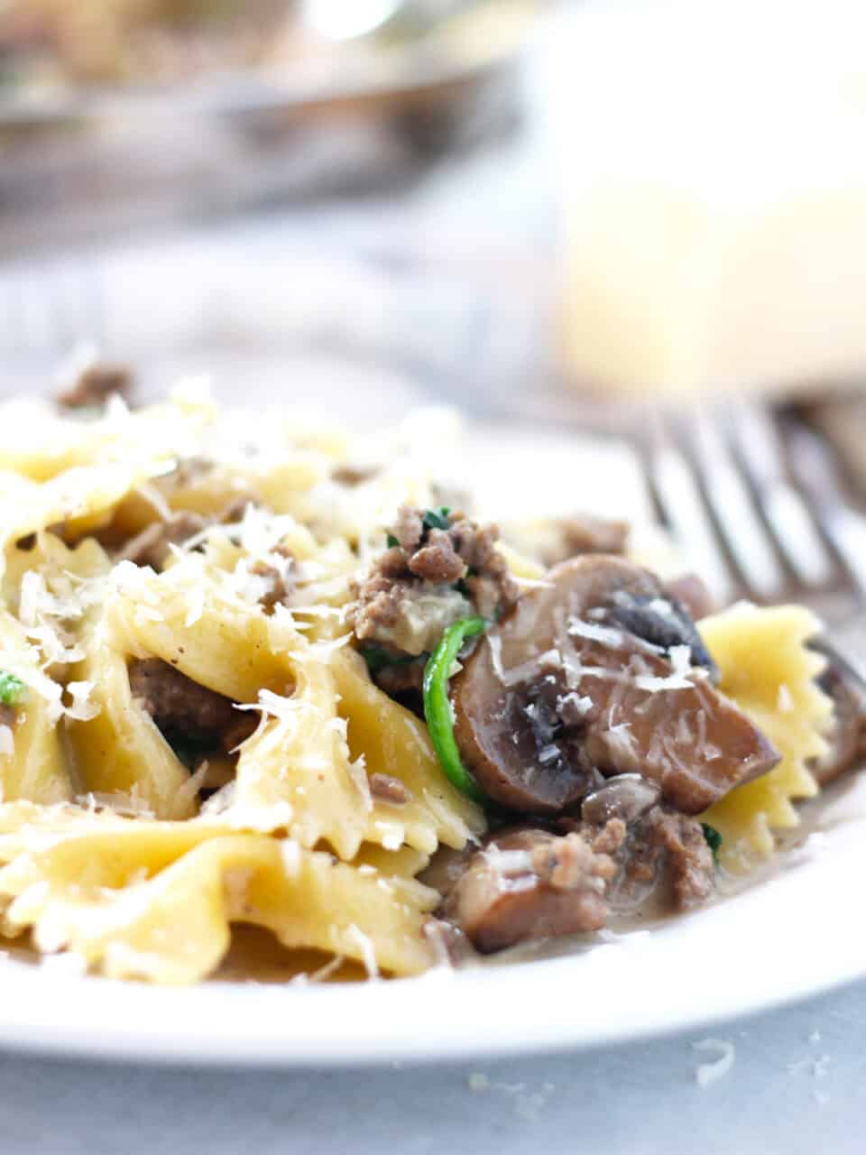 Close up of mushrooms, spinach, beef and pasta on a white plate.