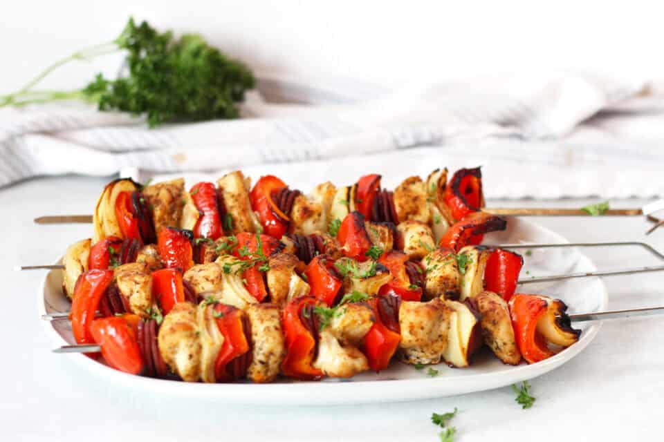 Chicken chorizo skewers served on a plate with fresh parsley garnish.