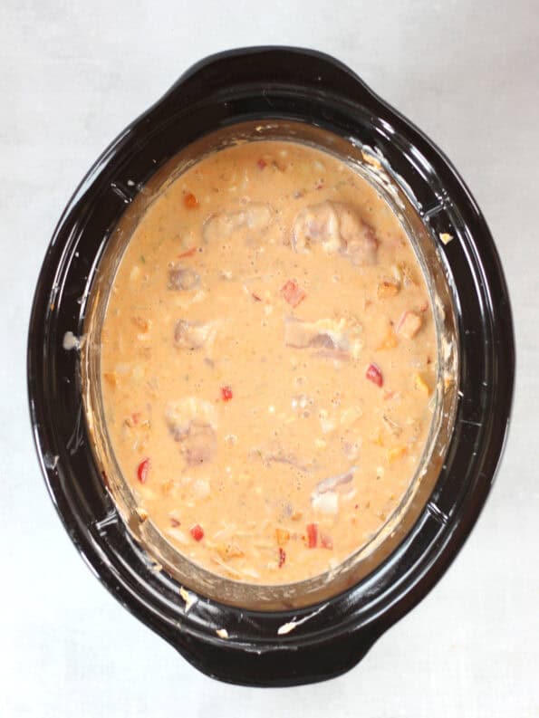Chicken thighs added to the coconut milk sauce in the slow cooker.