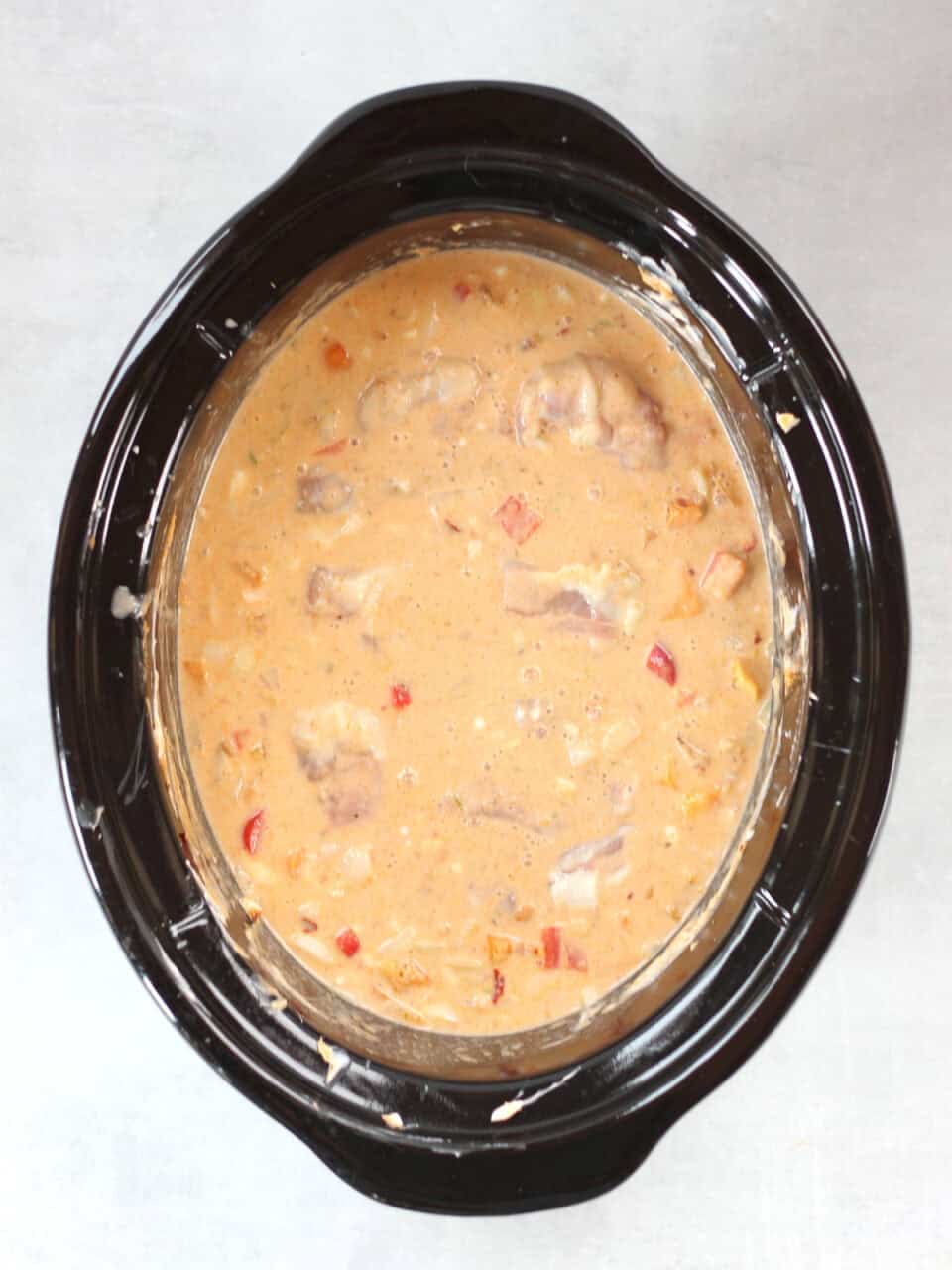 Chicken thighs added to the coconut milk sauce in the slow cooker.