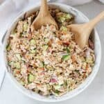 A bowl of pearl couscous chicken salad with serving spoons.