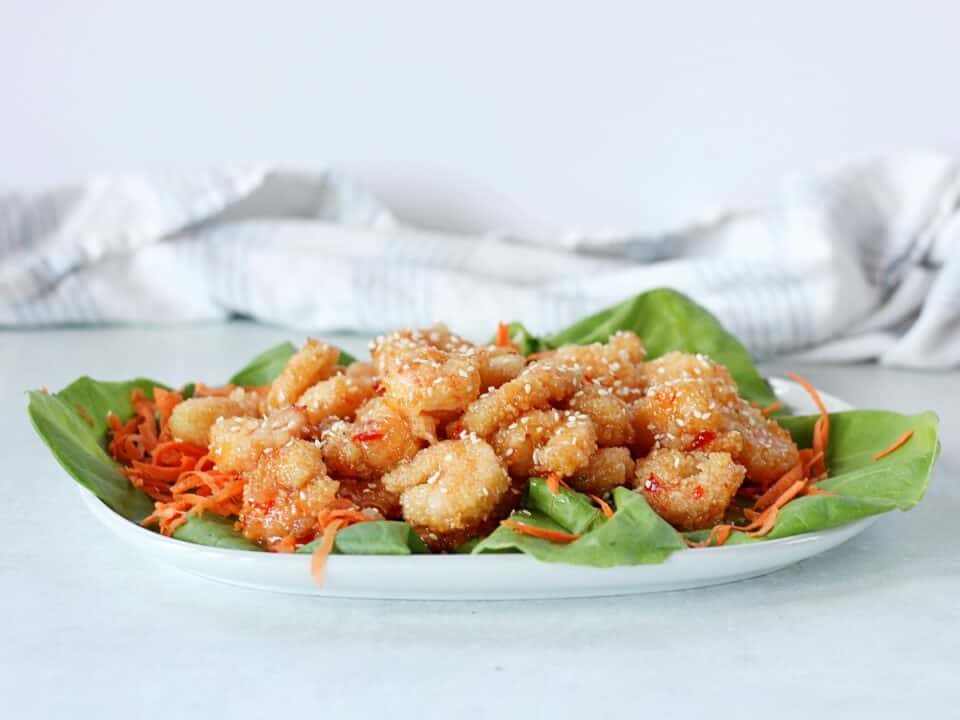 Thai crispy shrimp on a serving plate garnished with sesame seeds.