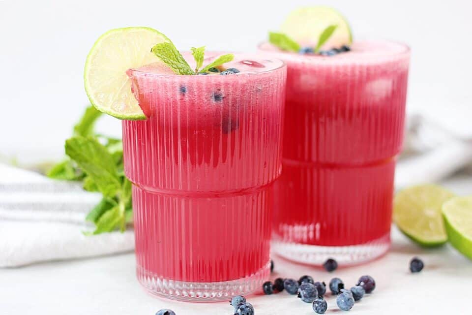 Two glasses of blueberry limeade with mint.