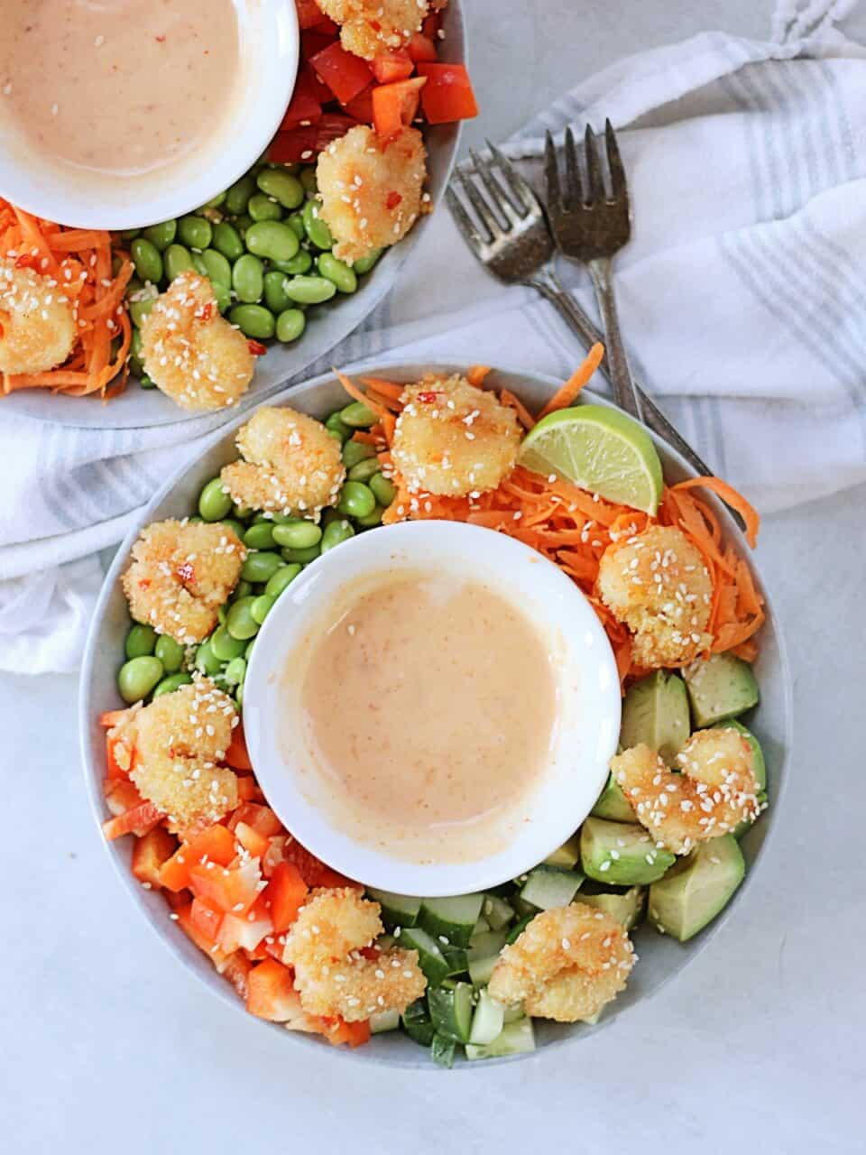 Two crispy shrimp rice bowls with bang bang sauce in the centre.