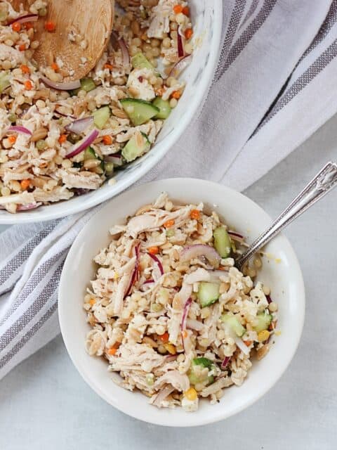 Shredded chicken couscous salad served in a small bowl with a fork.