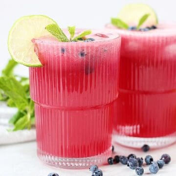 Blueberry limeade served in a glass with fresh garnishes.