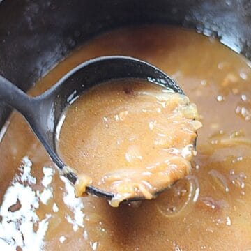Onion gravy in a black ladle.