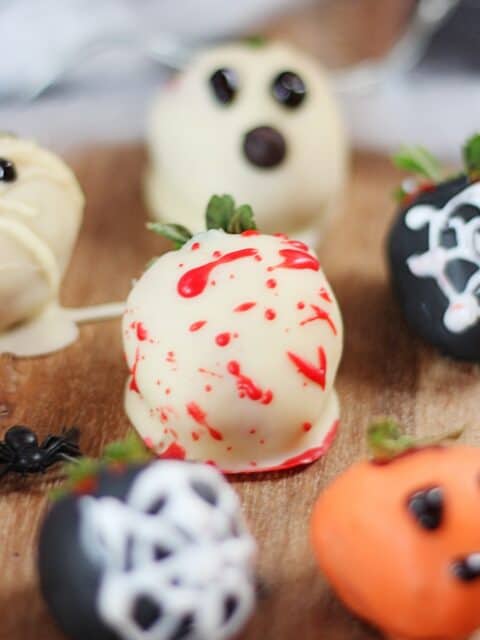 A strawberry coated in white chocolate with red blood splatters.