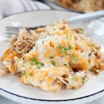 Cheesy beef casserole served on a white plate and garnished with fresh chives.