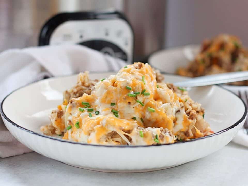 Crockpot ground beef and rice with melted cheese and fresh chives.