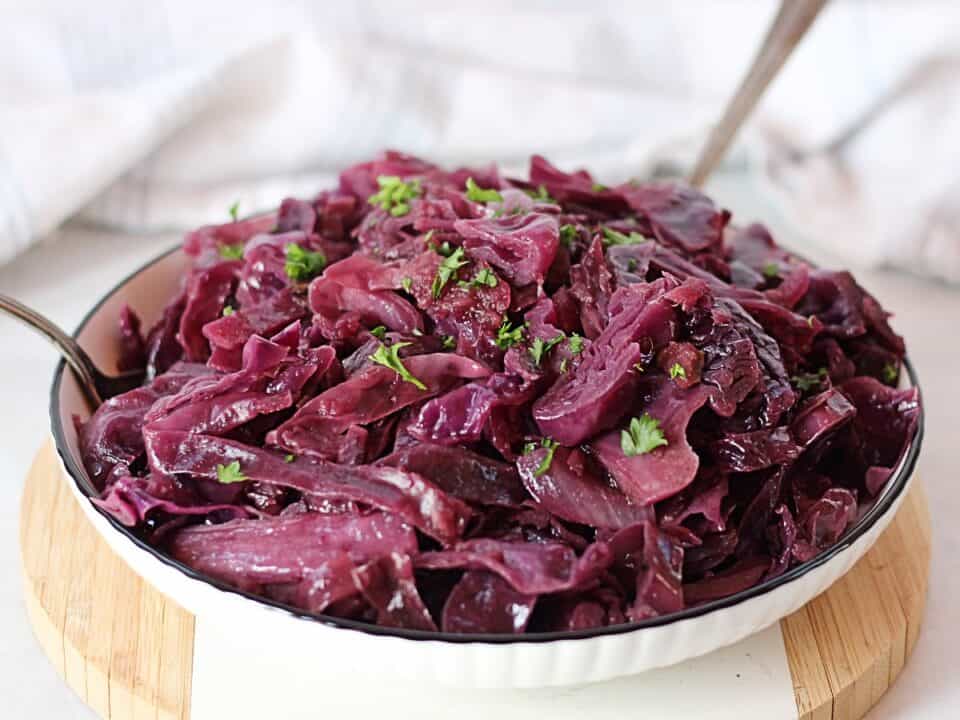 Braised red cabbage in a serving bowl with parsley garnish.