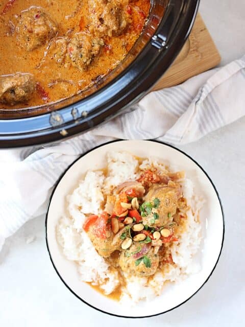 Meatballs and Thai curry served on a plate with rice.
