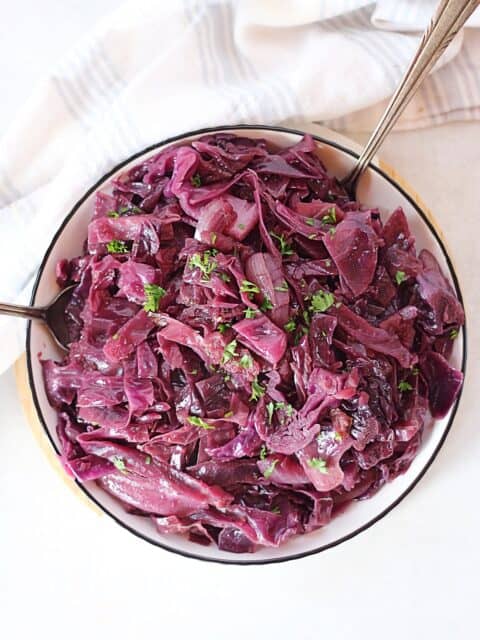 Slow cooker braised red cabbage served in a bowl with two spoons.