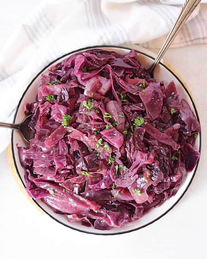 Slow cooker braised red cabbage served in a bowl with two spoons.