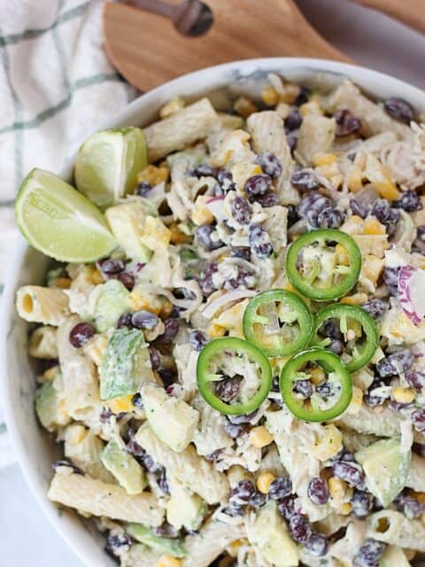 Sliced jalapenos and lime wedges on a pasta salad.