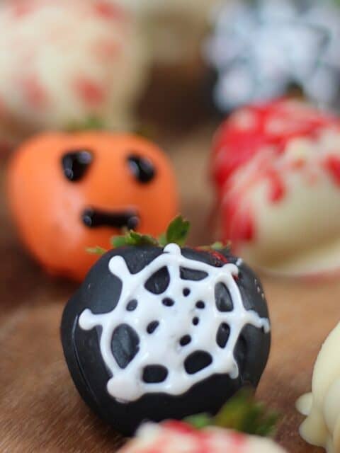 Spiderweb and pumpkin decorated strawberries.