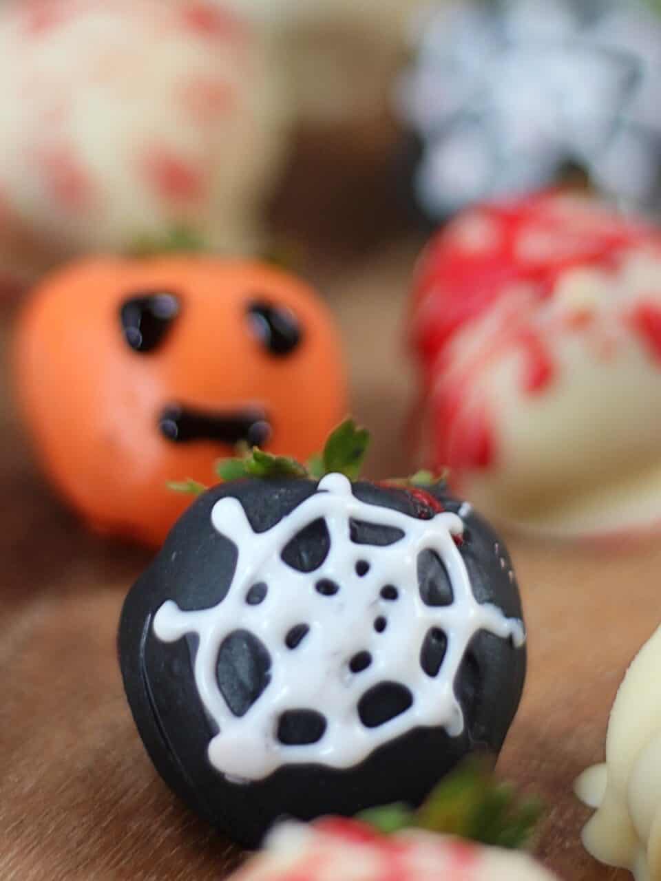 Spiderweb and pumpkin decorated strawberries.